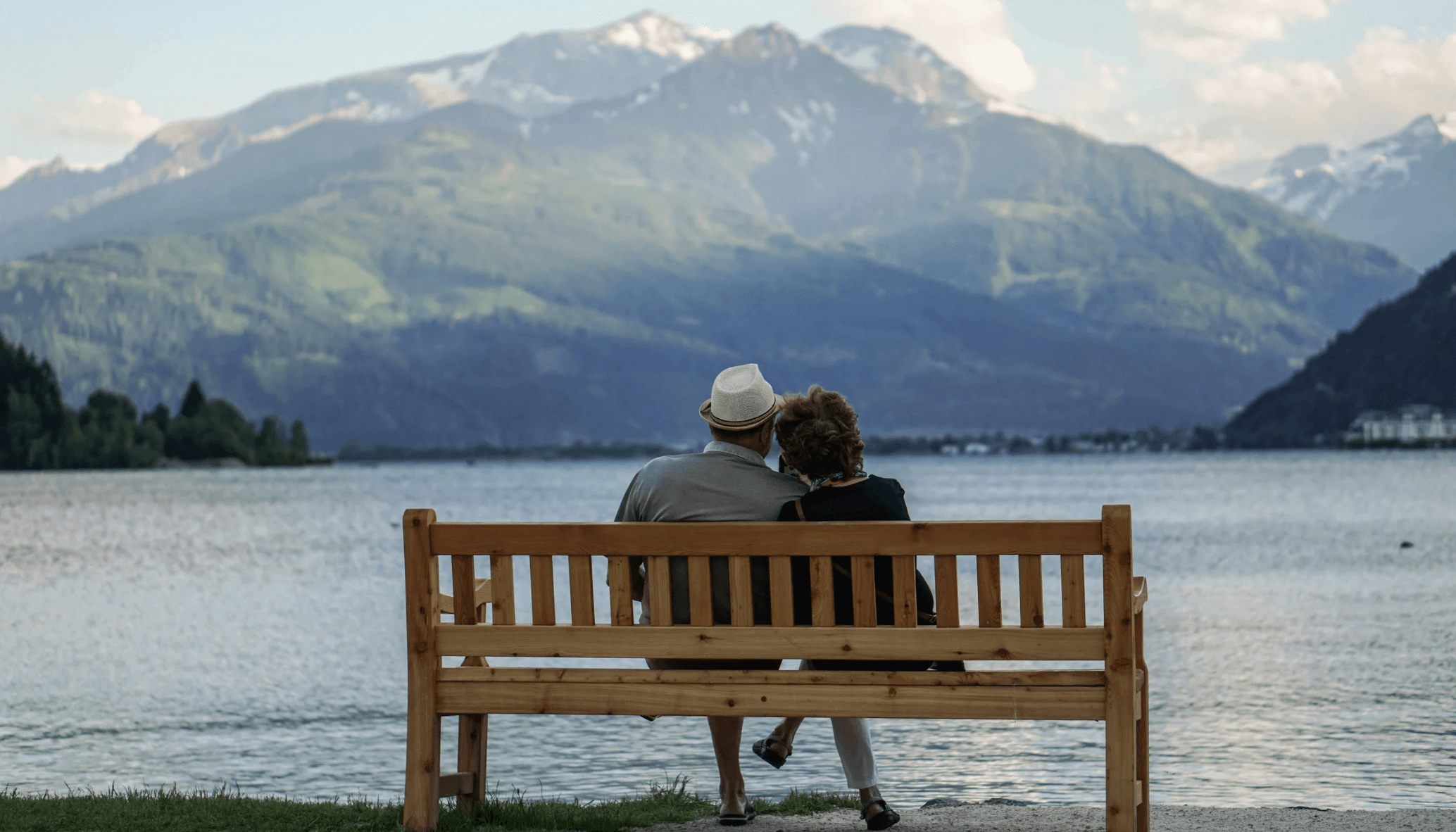 Couple on a bench looking at a lake and mountains